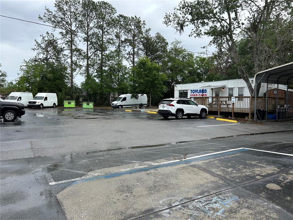 A white office building with a wooden deck sits in a paved parking lot — 241 NE 39TH AVENUE, GAINESVILLE, FL