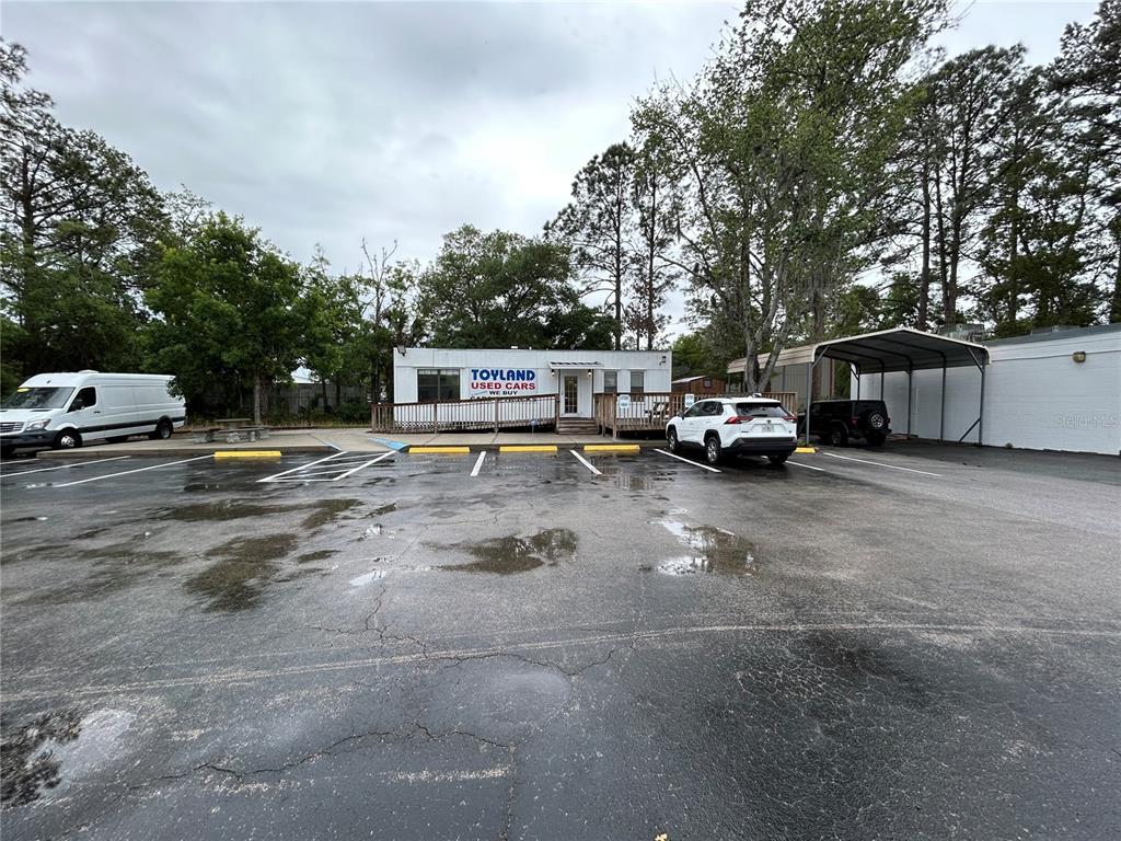 A white commercial building with a parking lot and a metal carport — 241 NE 39TH AVENUE, GAINESVILLE, FL