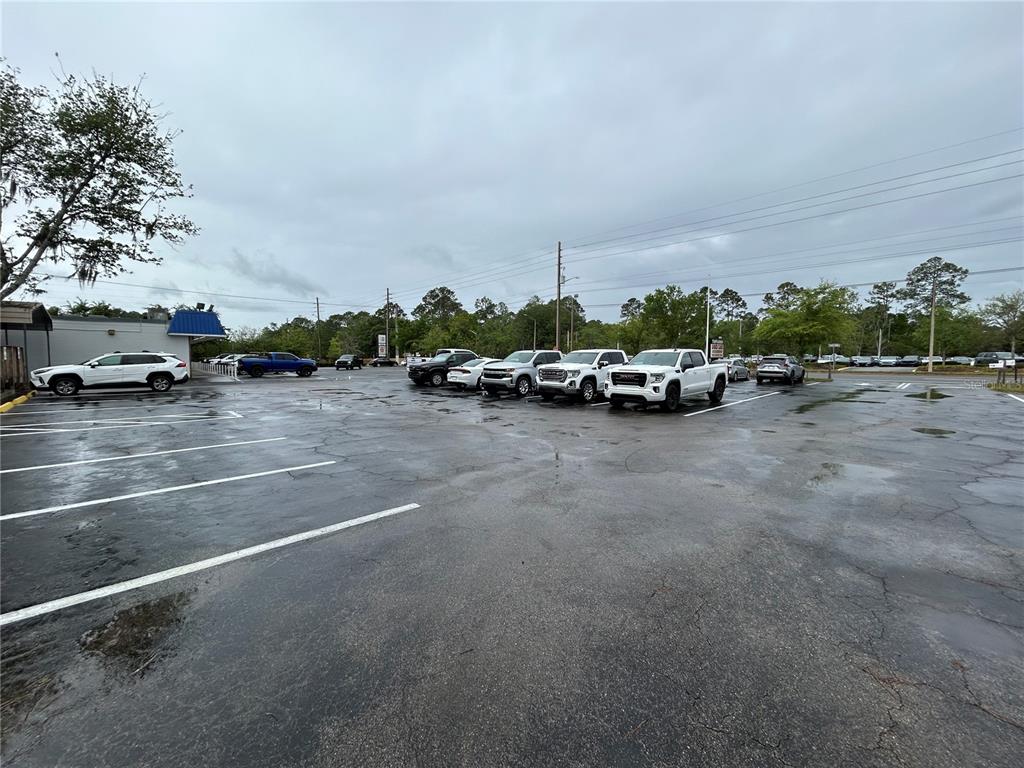 A paved parking lot with several parked vehicles under a cloudy sky — 241 NE 39TH AVENUE, GAINESVILLE, FL