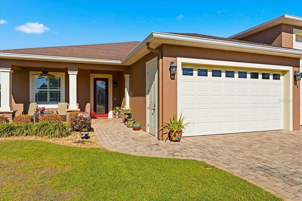 A brown house exterior features a white garage door, a paved walkway, and a front porch — 719 TEABERRY TRAIL, POLK CITY, FL