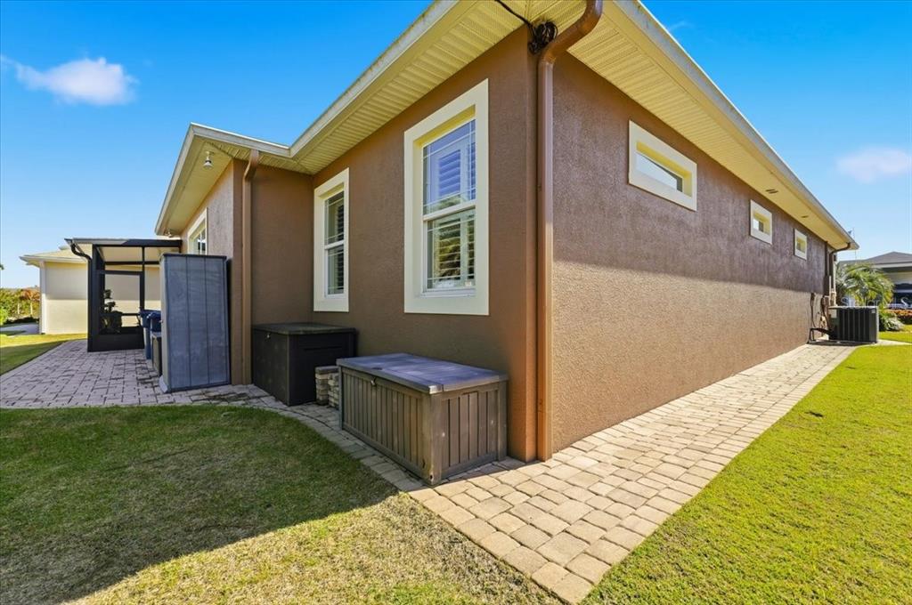 The exterior of a brown stucco house features a paver walkway and storage bins — 719 TEABERRY TRAIL, POLK CITY, FL
