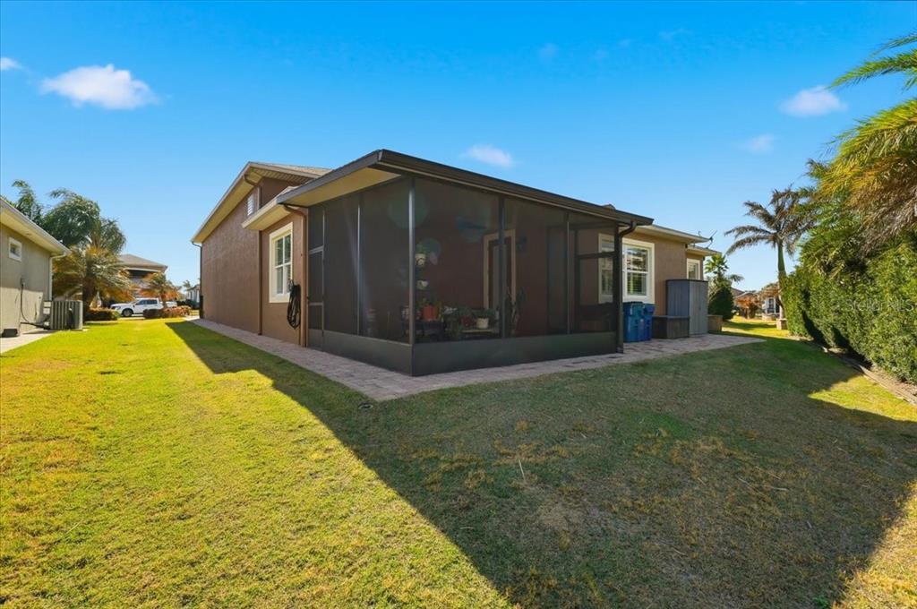 A brown house features a screened-in patio and a paved walkway on a grassy lawn — 719 TEABERRY TRAIL, POLK CITY, FL