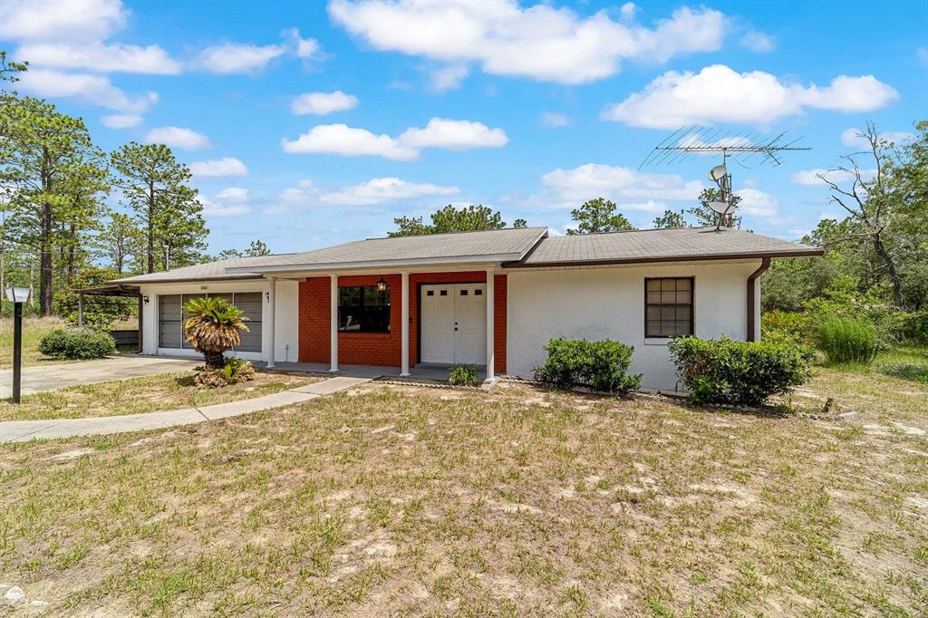 A single-story house with a white exterior, red brick accents, and an attached garage — 23063 SW EDGEWATER BOULEVARD, DUNNELLON, FL