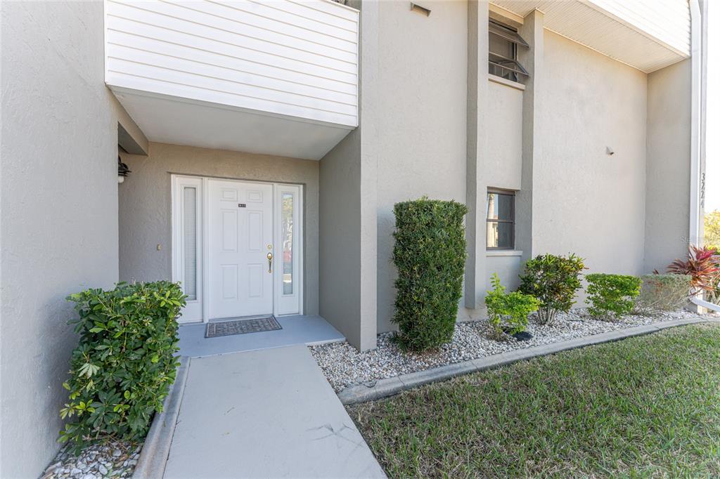 A concrete walkway leads to the white front door of a multi-story residential building — 3224 WHITE IBIS COURT UNIT B1-3, PUNTA GORDA, FL