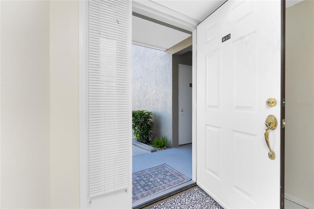 An open white door reveals a view of an outdoor walkway and a neighboring unit — 3224 WHITE IBIS COURT UNIT B1-3, PUNTA GORDA, FL