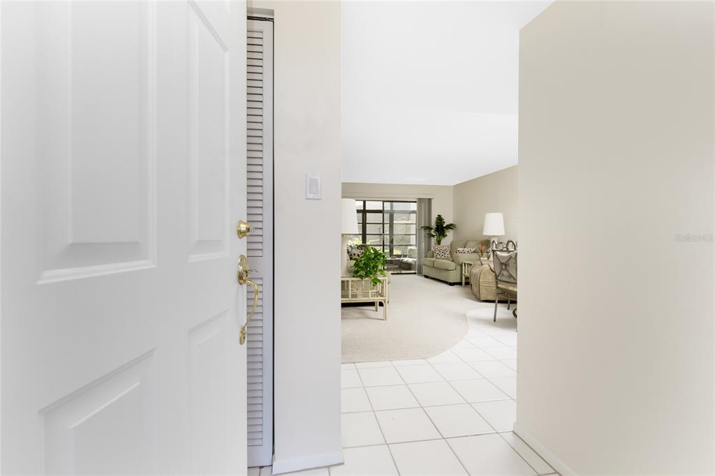 A view from a doorway looking into a living room with tile flooring and carpet — 3224 WHITE IBIS COURT UNIT B1-3, PUNTA GORDA, FL