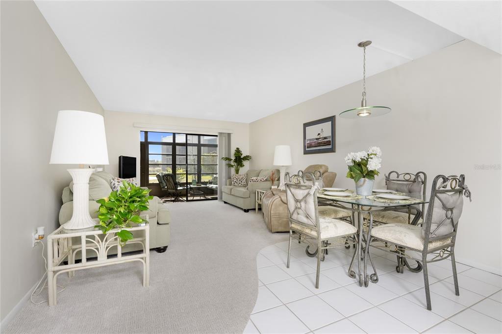 A living and dining area with carpeted floors, tiled dining space, and sliding glass doors — 3224 WHITE IBIS COURT UNIT B1-3, PUNTA GORDA, FL
