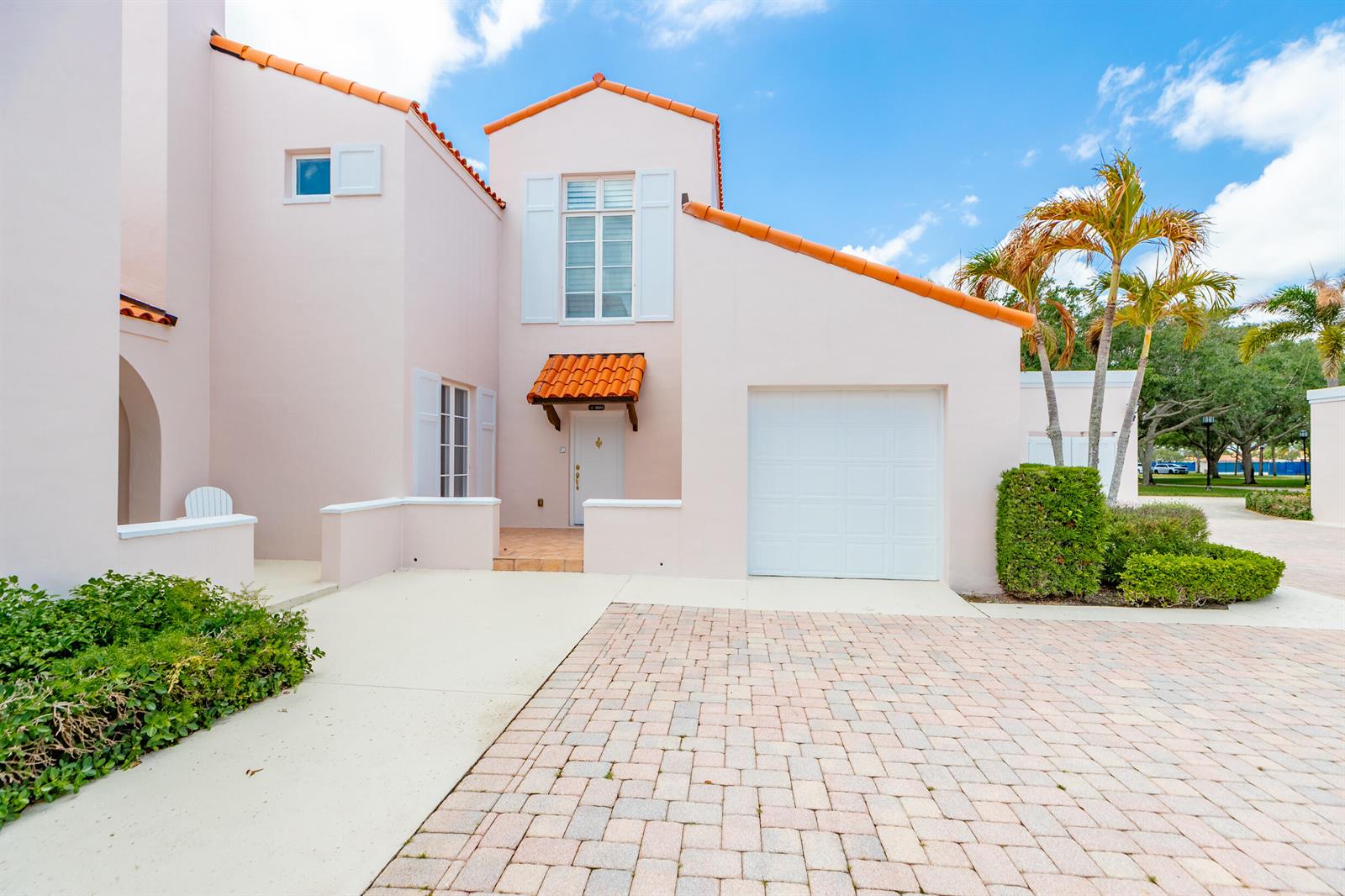 A light pink two-story house features a white garage door, tiled roof, and paved driveway — VERO BEACH, FL