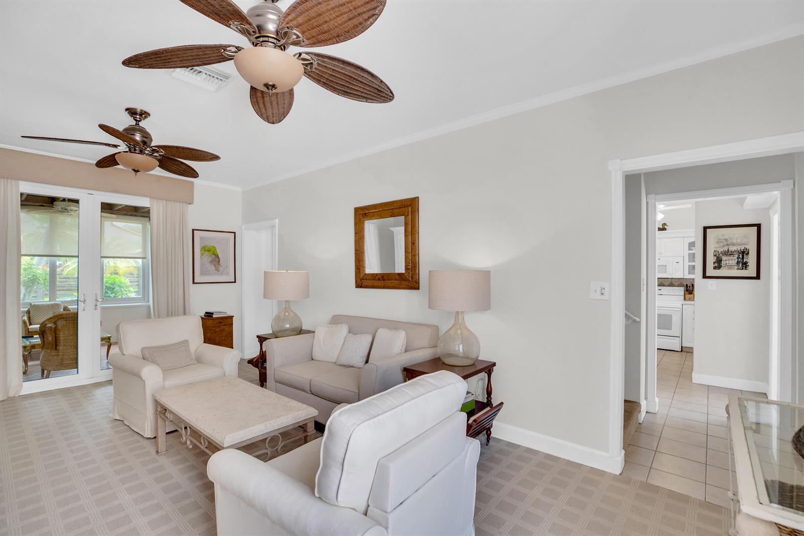A living room features two ceiling fans, neutral furniture, and a doorway leading to a kitchen — VERO BEACH, FL