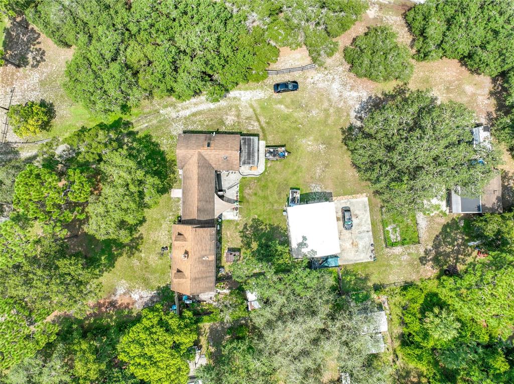 An aerial view shows a house with a brown roof, a detached garage, and surrounding trees — 670 E STATE ROAD 46, GENEVA, FL