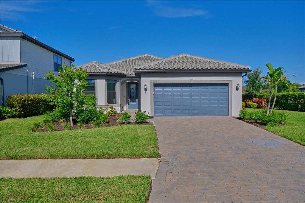 A single-story house with a blue garage door, tiled roof, and a paved driveway — 818 PINTAIL COVE, BRADENTON, FL