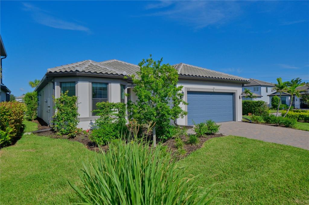 A single-story house with a blue garage door, gray roof, and a landscaped front yard — 818 PINTAIL COVE, BRADENTON, FL