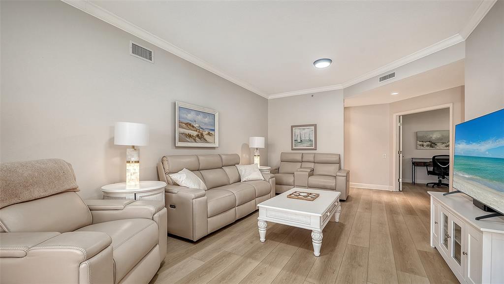 A living room features light-colored leather furniture, a white coffee table, and wood-look flooring — 5235 PARISIENNE PLACE UNIT 101B28, SARASOTA, FL
