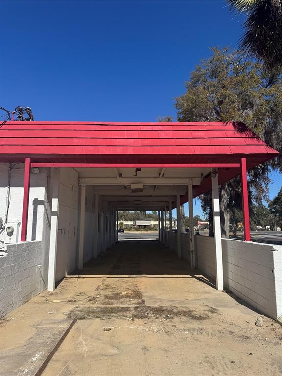 An exterior view of a covered drive-through area with a red roof and white pillars — 3680 E SILVER SPRINGS BOULEVARD, OCALA, FL