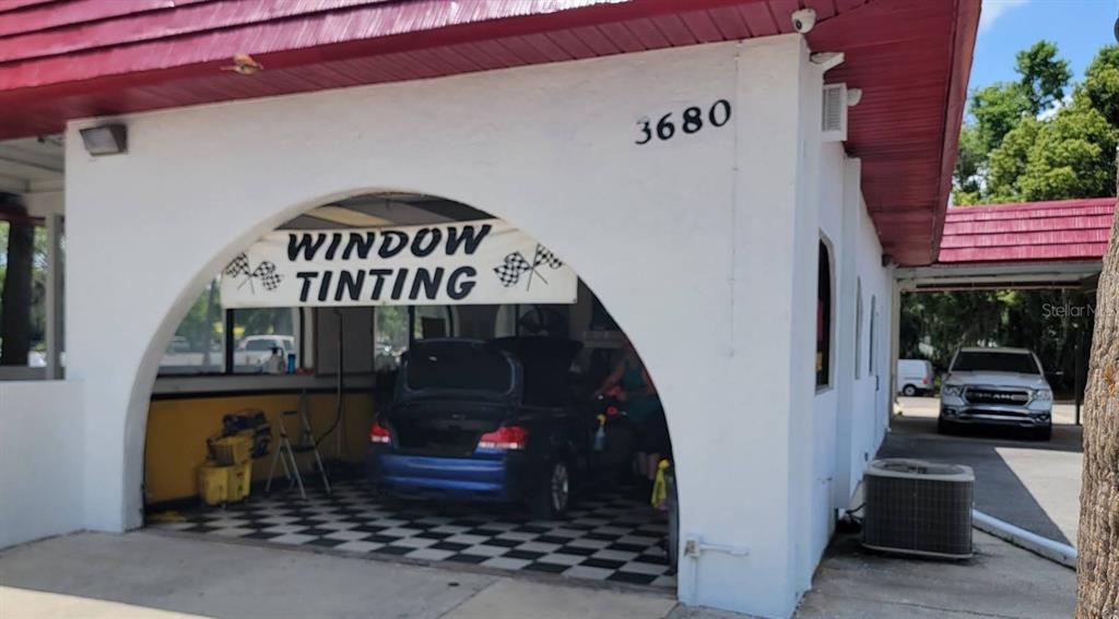 An exterior view of a commercial building with a window tinting sign and service bay — 3680 E SILVER SPRINGS BOULEVARD, OCALA, FL