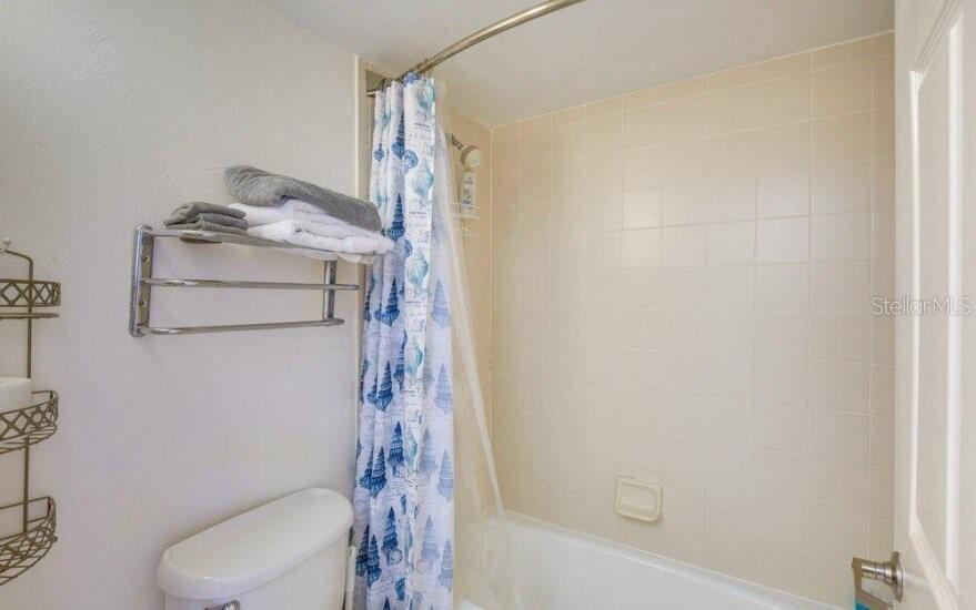 A bathroom features a white toilet, a towel rack, and a shower with a patterned curtain — 2700 N ATLANTIC AVENUE UNIT 421, DAYTONA BEACH, FL