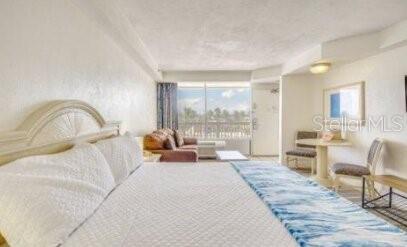 A bedroom with a large bed, a small seating area, and a view of the outdoors — 2700 N ATLANTIC AVENUE UNIT 421, DAYTONA BEACH, FL