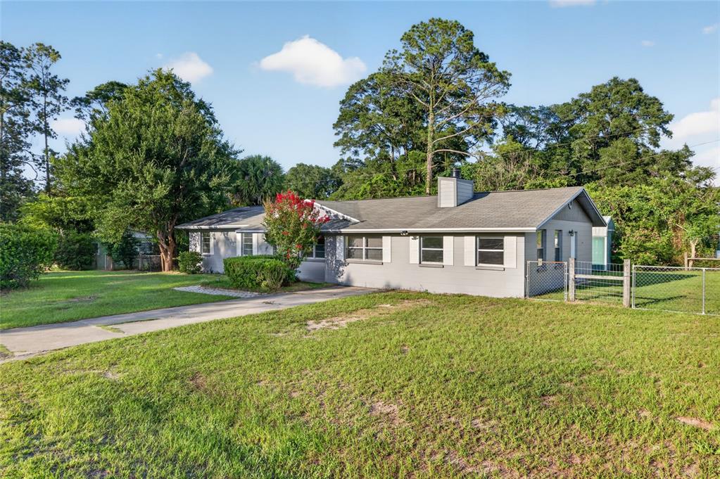 A single-story gray house with a driveway and a fenced yard under a blue sky — 17409 NW 240TH TERRACE, HIGH SPRINGS, FL
