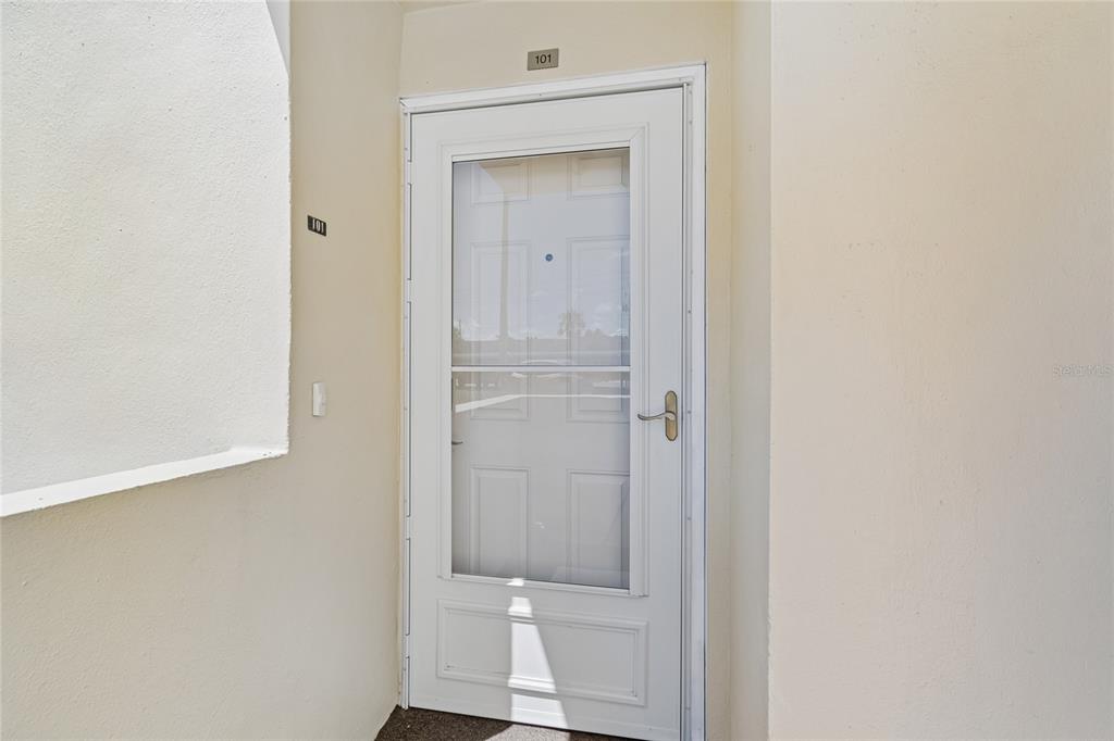 A white storm door with a glass panel is installed at the entrance of unit 101 — 4575 COVE CIRCLE UNIT 101, ST PETERSBURG, FL