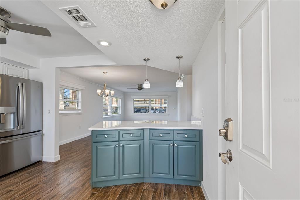 A kitchen island with blue cabinets and a white countertop faces a living area — 4575 COVE CIRCLE UNIT 101, ST PETERSBURG, FL