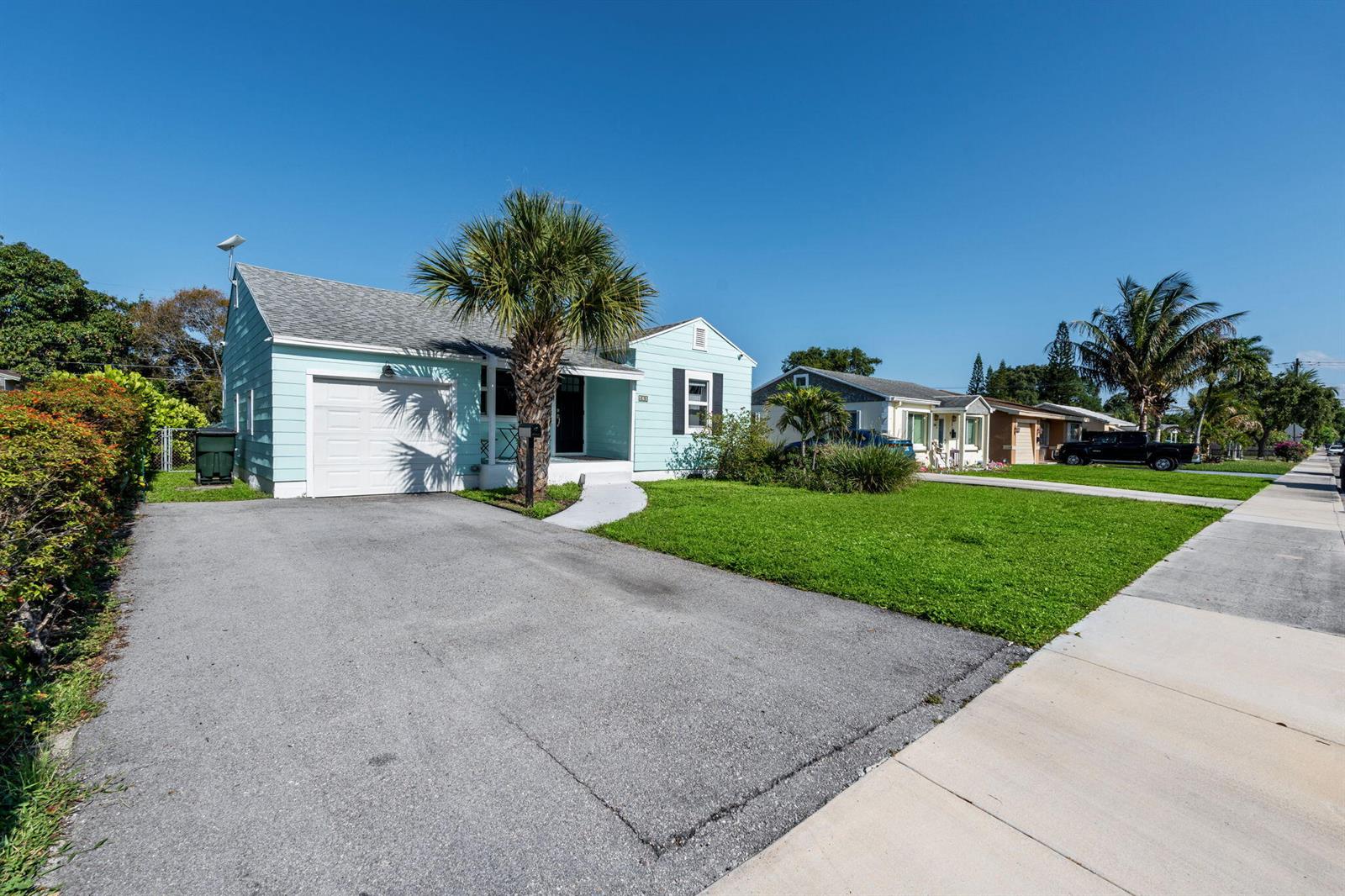 A light blue single-story house with a driveway, a palm tree, and a green lawn — 620 N B Street, FL 33460, FL