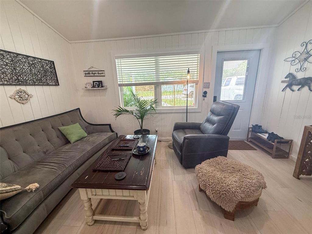 A living room features a gray tufted sofa, a dark wood coffee table, and a recliner — 11770 N ANGUS HILLS TERRACE, DUNNELLON, FL