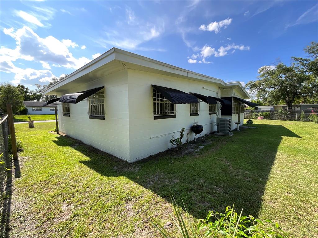 The exterior of a white concrete block house features black metal window awnings and security bars — 2423 SAVOY DRIVE, ORLANDO, FL