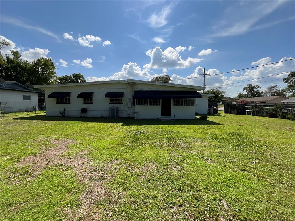 A single-story house with a white exterior and dark awnings sits on a grassy lot — 2423 SAVOY DRIVE, ORLANDO, FL