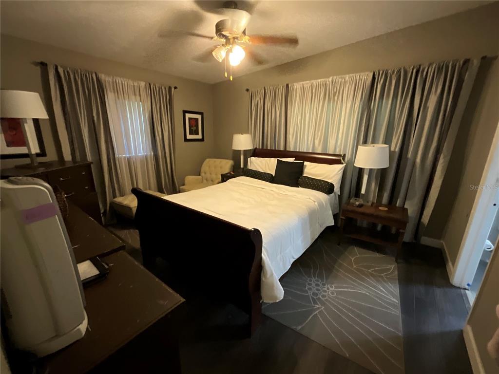A bedroom features a dark wood bed frame, white bedding, two nightstands, and gray curtains — 2423 SAVOY DRIVE, ORLANDO, FL