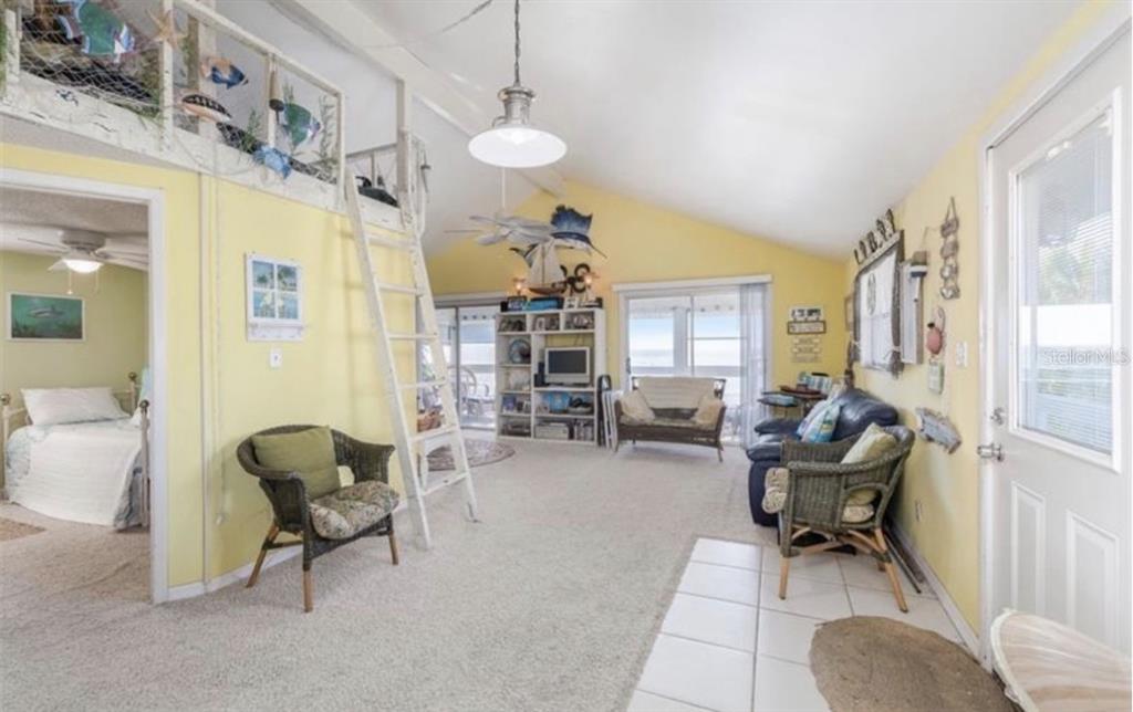 A living room with yellow walls, a loft area with a ladder, and carpeted flooring — 3528 W SHELL POINT ROAD, RUSKIN, FL