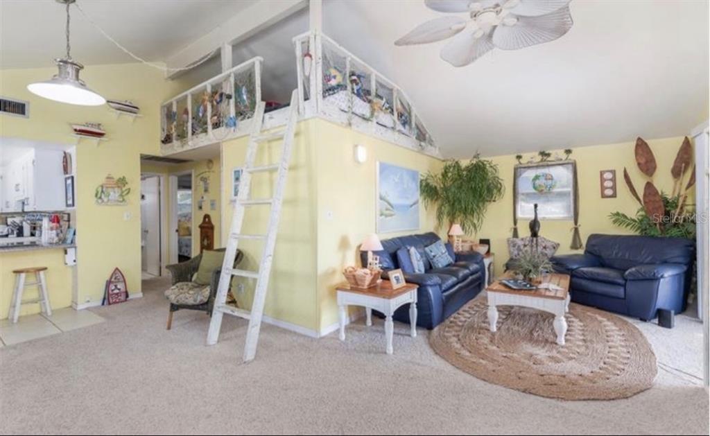 A living room features a loft area with a ladder, blue sofas, and yellow walls — 3528 W SHELL POINT ROAD, RUSKIN, FL