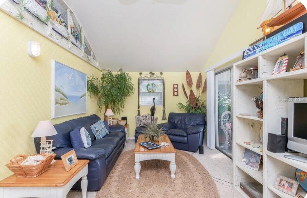 A living room with yellow walls, blue leather furniture, a coffee table, and a bookshelf — 3528 W SHELL POINT ROAD, RUSKIN, FL