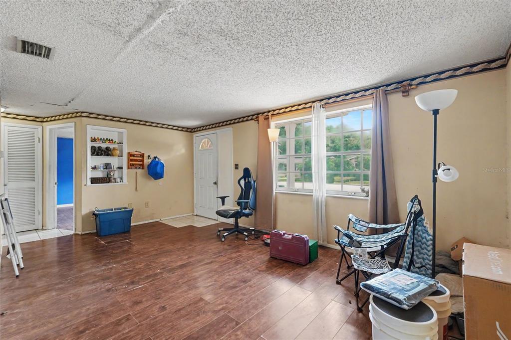 A room with wood-look flooring, a popcorn ceiling, a window, and a white door — 3317 BAINBRIDGE DRIVE, HOLIDAY, FL