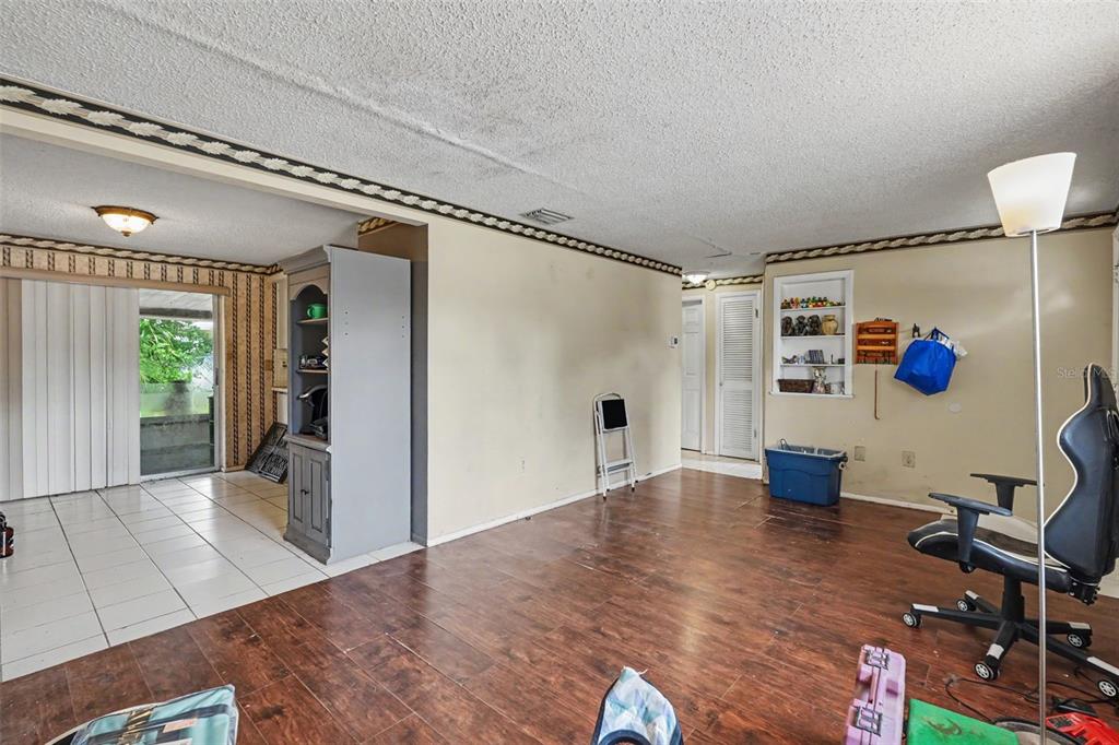 A room with wood-look flooring, a gray cabinet, a built-in shelf, and a sliding door — 3317 BAINBRIDGE DRIVE, HOLIDAY, FL