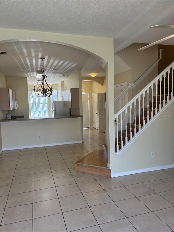 An interior view shows a tiled floor, a staircase with white railings, and a kitchen area — 1237 S BEACH CIRCLE, KISSIMMEE, FL