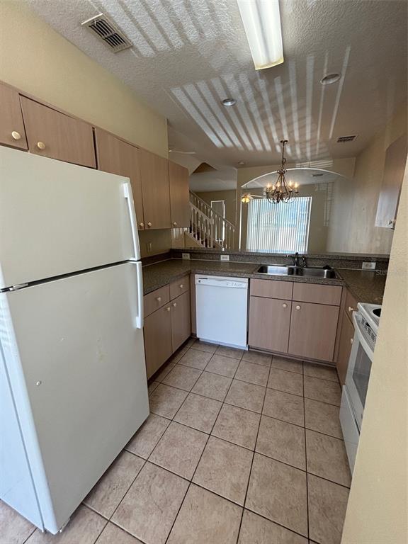 A kitchen features light wood cabinets, white appliances, tile flooring, and a breakfast bar — 1237 S BEACH CIRCLE, KISSIMMEE, FL
