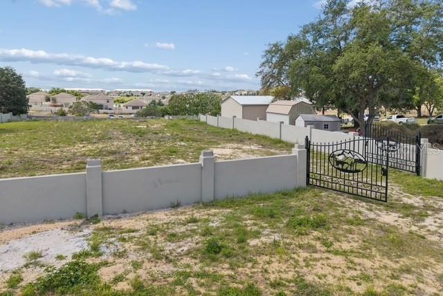An aerial view shows a fenced, vacant lot with a metal gate and storage sheds — 1501 NORTH BOULEVARD W, DAVENPORT, FL