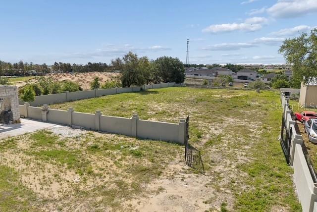 An elevated view of a vacant, fenced-in lot with sparse grass and sandy soil — 1501 NORTH BOULEVARD W, DAVENPORT, FL