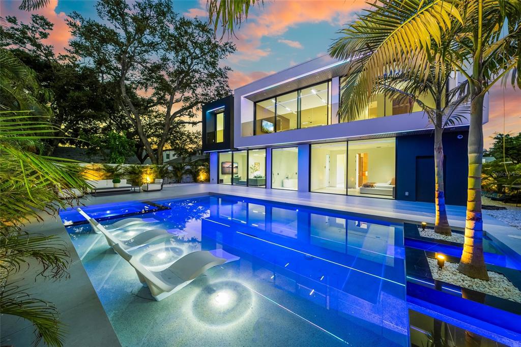 A modern two-story house with a swimming pool featuring built-in lounge chairs at dusk — 1640 WALDEMERE STREET, SARASOTA, FL