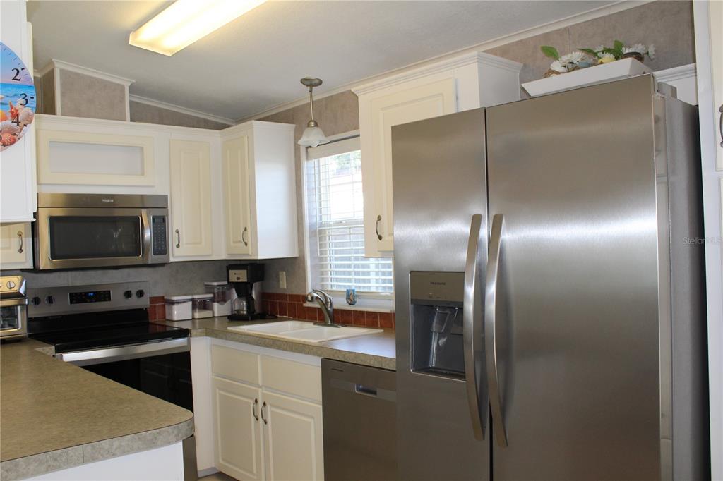 A kitchen features white cabinets, stainless steel appliances, a double sink, and a window — 12 SADDLEBAG TRAIL, LAKE WALES, FL