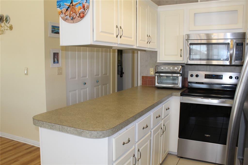 A kitchen features white cabinets, stainless steel appliances, and a laminate countertop — 12 SADDLEBAG TRAIL, LAKE WALES, FL