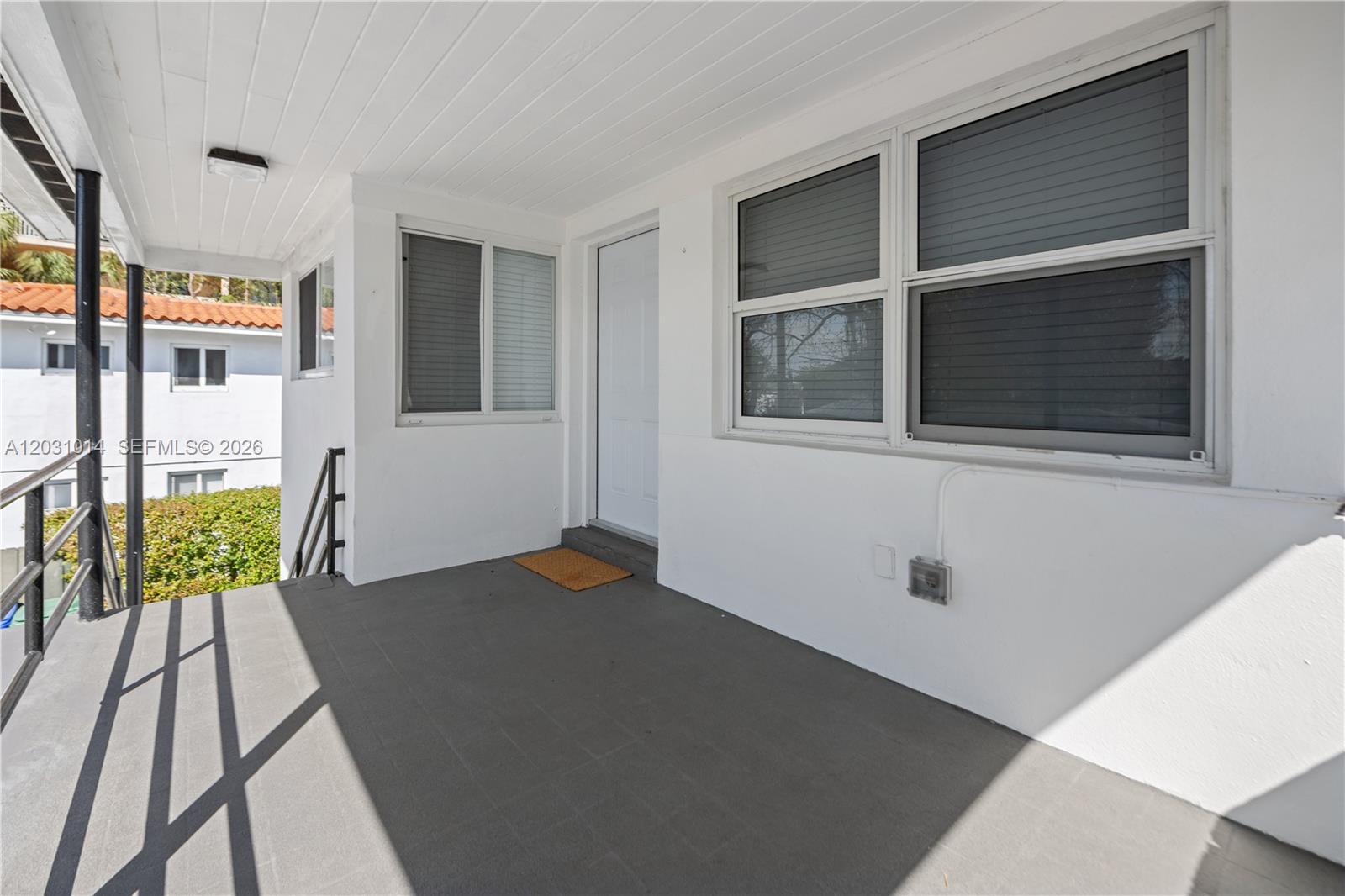 A covered outdoor porch features gray tiled flooring, white walls, and a white entry door — 2240 SW 16th Ct # U, Miami FL 33145, MIAMI, FL