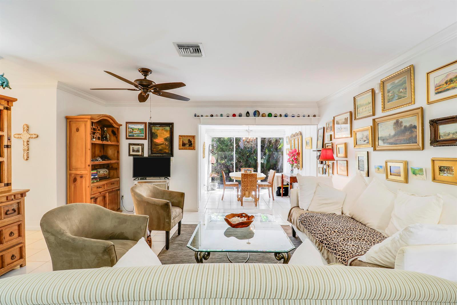 A living room features a white sofa, two armchairs, a glass coffee table, and gallery walls — 1329 Chippewa Street, Jupiter FL 33458, JUPITER, FL