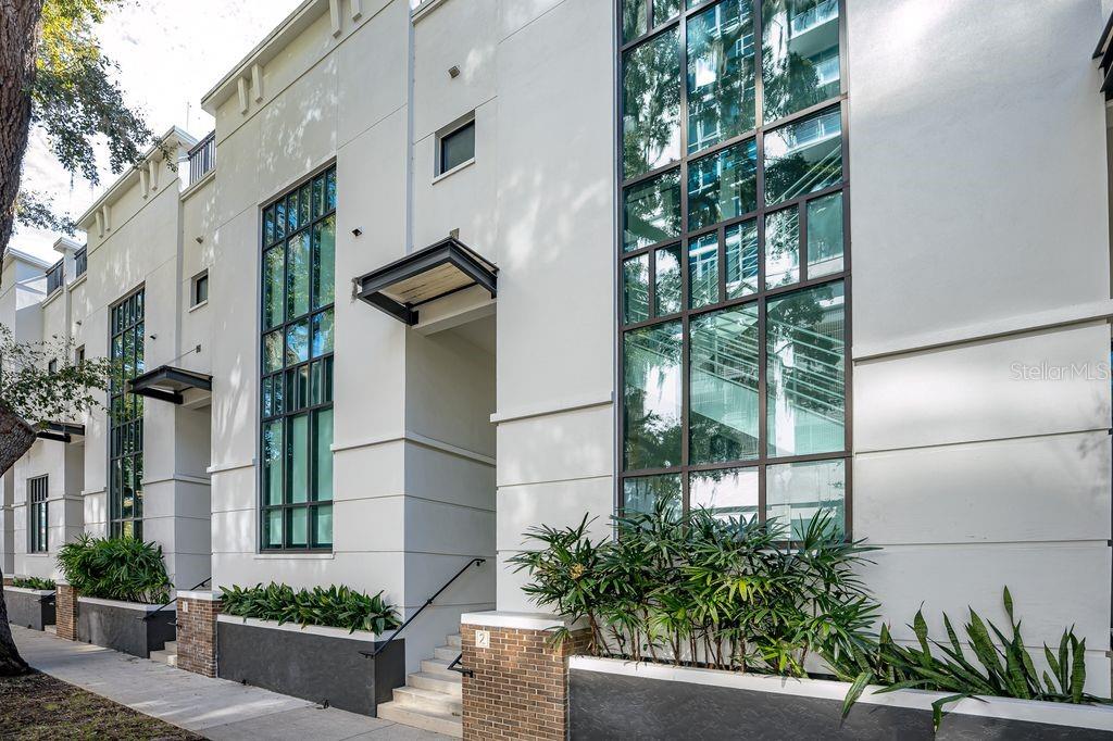 A modern white townhouse exterior features tall windows, brick accents, and a small front staircase — 460 E JACKSON STREET UNIT 2, ORLANDO, FL