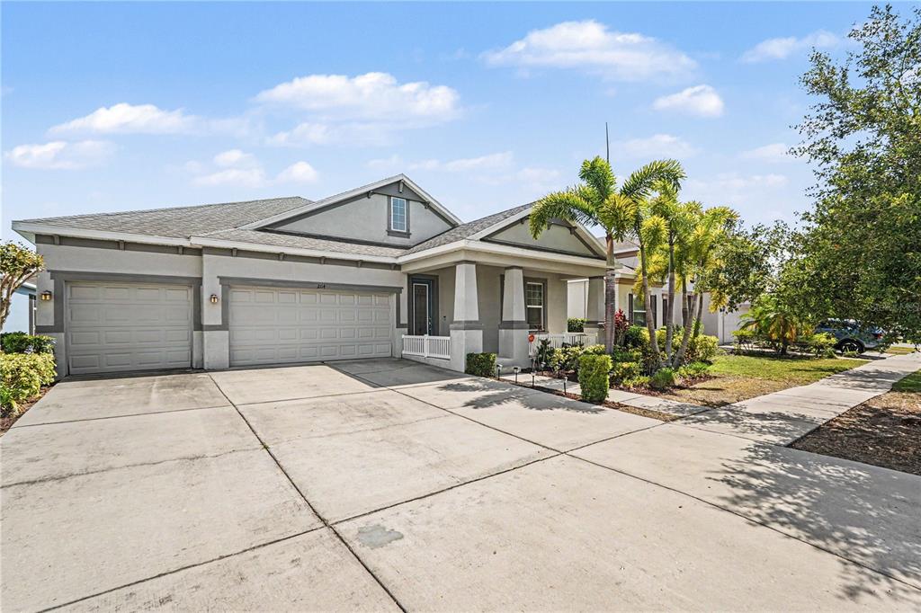 A single-story house with a two-car garage, a covered front porch, and palm trees — 204 SHELL CREEK COURT, APOLLO BEACH, FL