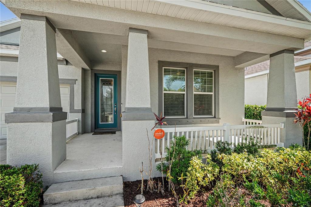 A front porch with a teal door, white railing, and tapered columns on a house — 204 SHELL CREEK COURT, APOLLO BEACH, FL