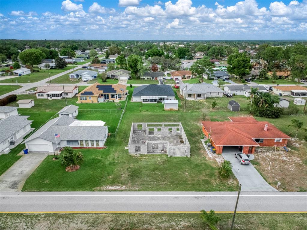 An aerial view shows a residential street with a concrete block house frame under construction — 229 WHATLEY BOULEVARD, SEBRING, FL