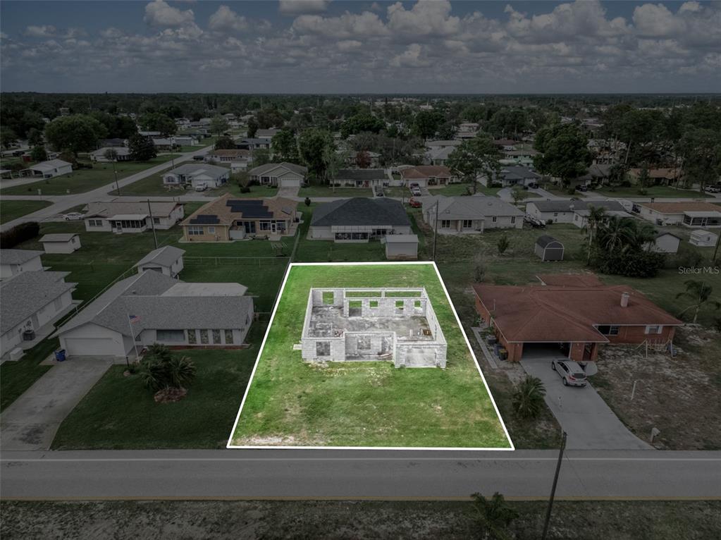 An aerial view shows a vacant lot with the concrete block walls of an unfinished house — 229 WHATLEY BOULEVARD, SEBRING, FL