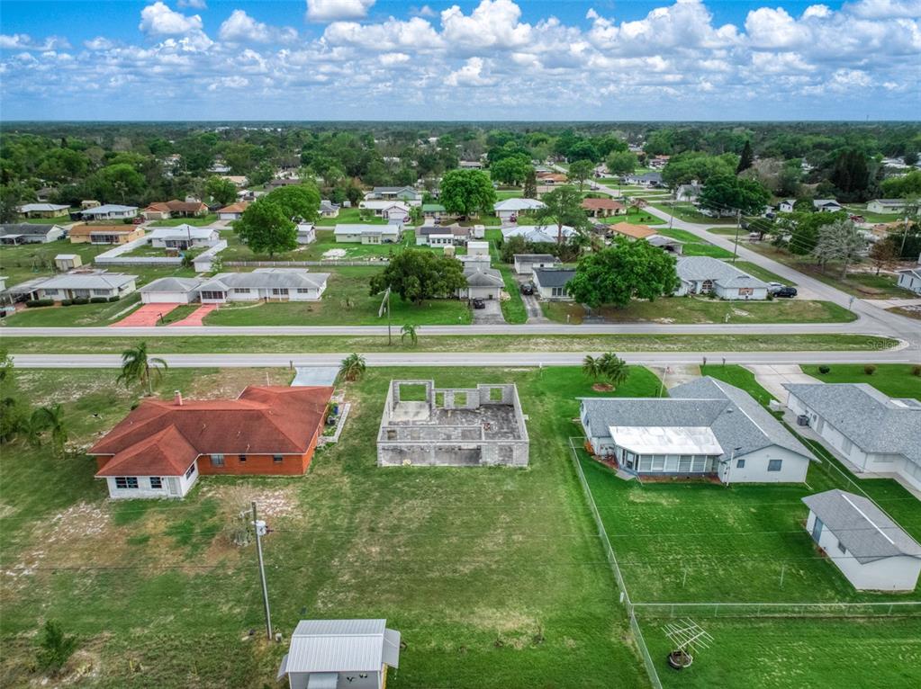 An aerial view shows a vacant concrete block foundation situated between two residential houses — 229 WHATLEY BOULEVARD, SEBRING, FL
