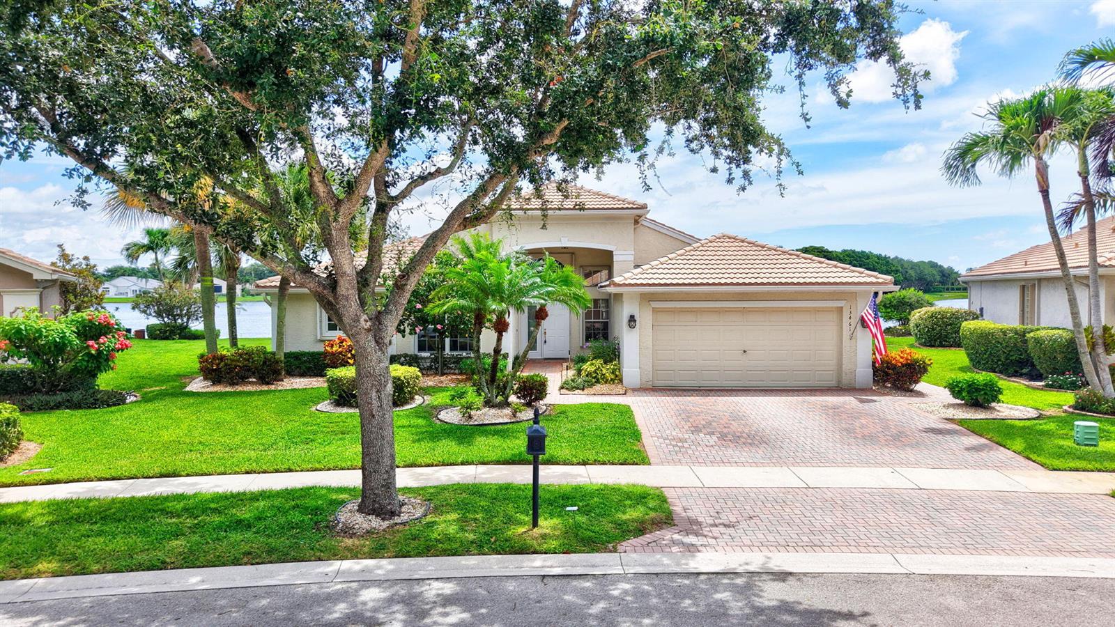 A single-story house with a brick driveway, a two-car garage, and a large front tree — 13461 Barcelona Lake Circle, Delray Beach FL 33446, DELRAY BEACH, FL